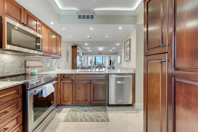 a kitchen with stainless steel appliances granite countertop a refrigerator a stove and a sink