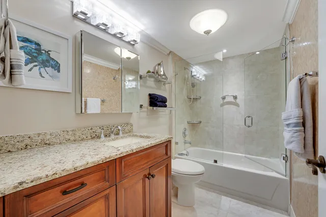 a bathroom with a granite countertop sink a toilet a mirror and bathtub