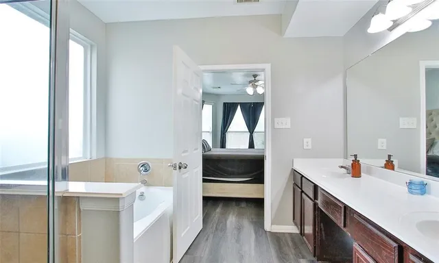 a en suite bathroom with a double vanity sink a mirror and bathtub