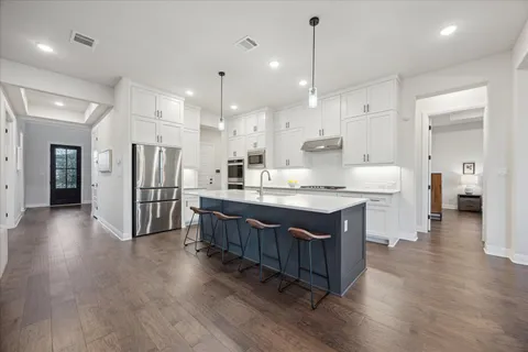 a large white kitchen with a large island in the center and white cabinets