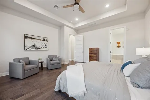 a bedroom with a bed couches and a flat screen tv