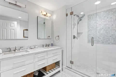 a bathroom with a double vanity sink mirror and shower