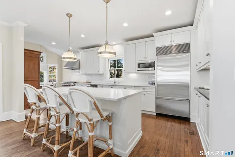 a kitchen with kitchen island granite countertop a refrigerator and a sink