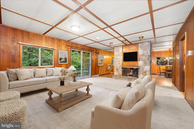 a living room with furniture a flat screen tv and floor to ceiling window