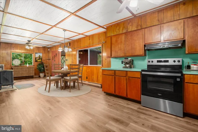 a kitchen with stainless steel appliances kitchen island granite countertop a table chairs in it and wooden floors