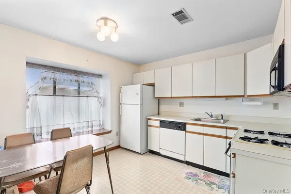 a kitchen with a stove a refrigerator and a dining table with wooden floor