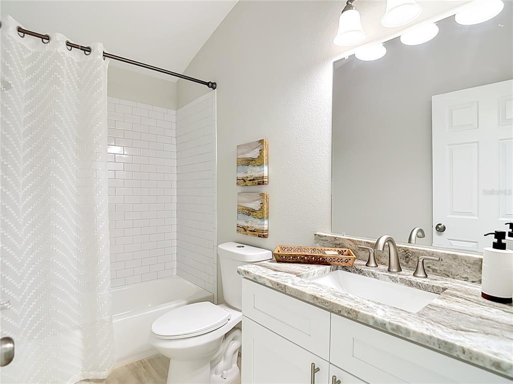 5310 Anhinga Trail New Port Richey, FL 34653 - Photo 21 of 27 a bathroom with a granite countertop sink a toilet and a mirror