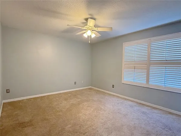 an empty room with a window and ceiling fan