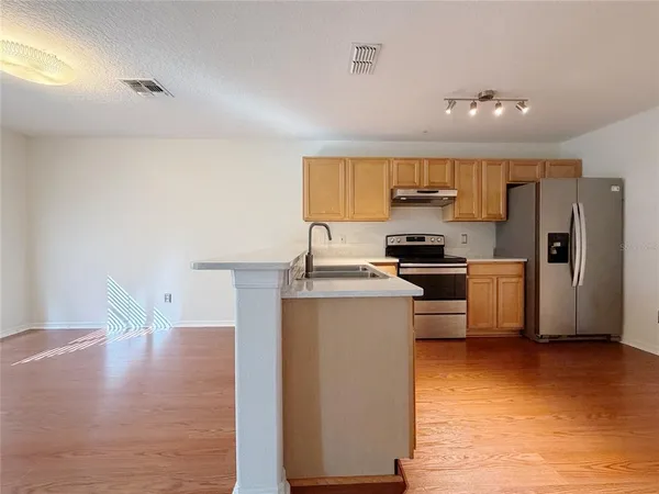 a kitchen with stainless steel appliances wooden floor and a refrigerator