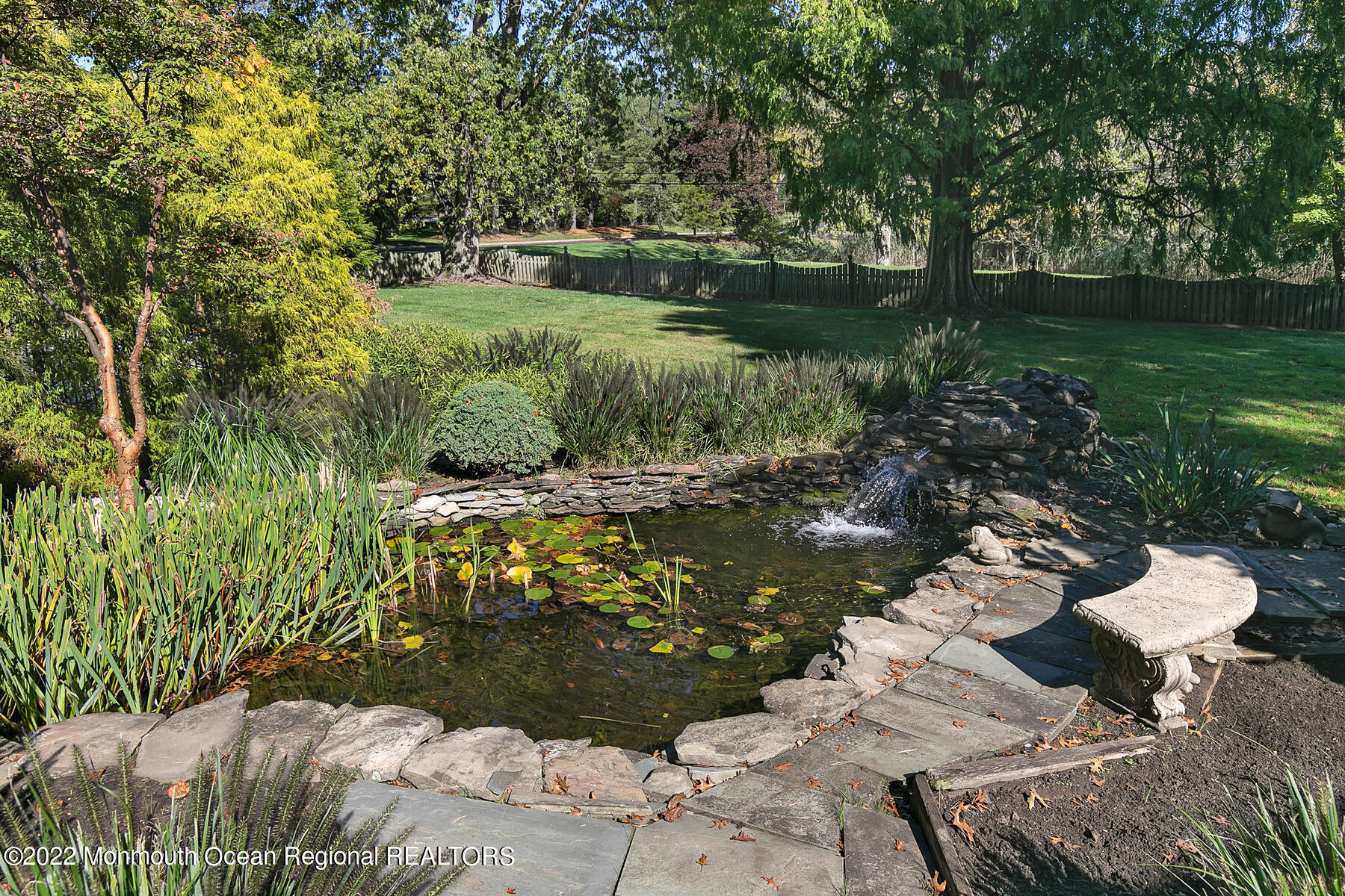 25 Spring Garden Avenue Colts Neck, NJ 07722 - Photo 46 of 58 a view of a garden with lawn chairs under an umbrella