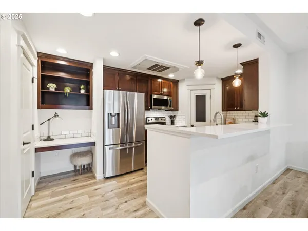 a kitchen with stainless steel appliances kitchen island granite countertop a refrigerator and a sink