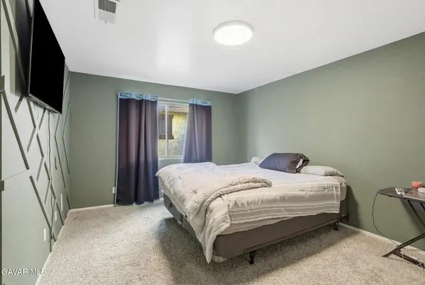 a bedroom with a bed flat screen tv and window