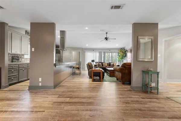 a living room with couches and kitchen view with wooden floor