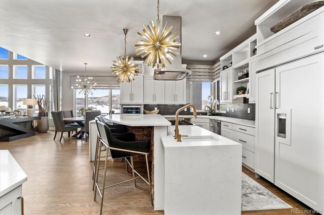 a kitchen with stainless steel appliances granite countertop a refrigerator a sink dishwasher a dining table and chairs with wooden floor