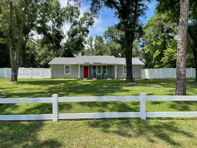 a view of a house with a yard and large trees