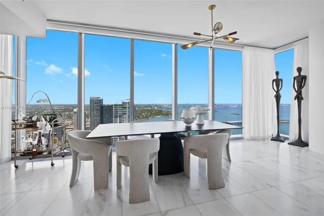 a kitchen with stainless steel appliances kitchen island granite countertop a refrigerator a stove a microwave and a dining table with wooden floor