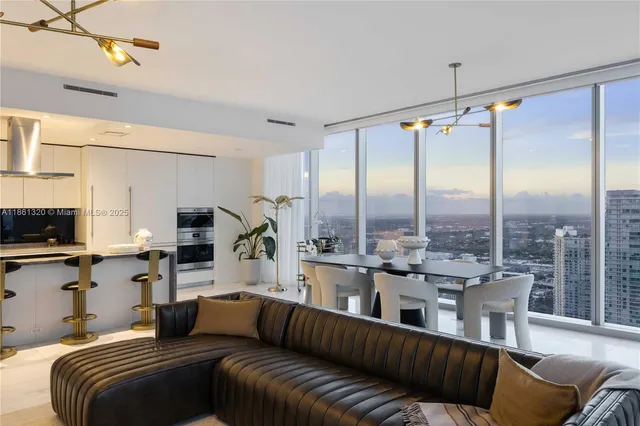 a living room with couches a flat screen tv and kitchen view