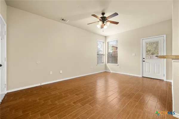 a view of an empty room with chandelier fan and wooden floor