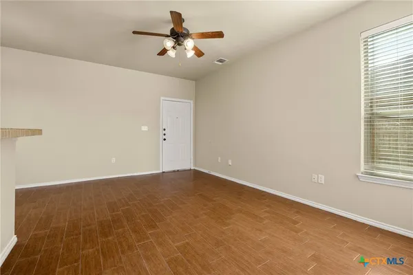 an empty room with a chandelier fan and windows