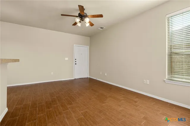 an empty room with a chandelier fan and windows