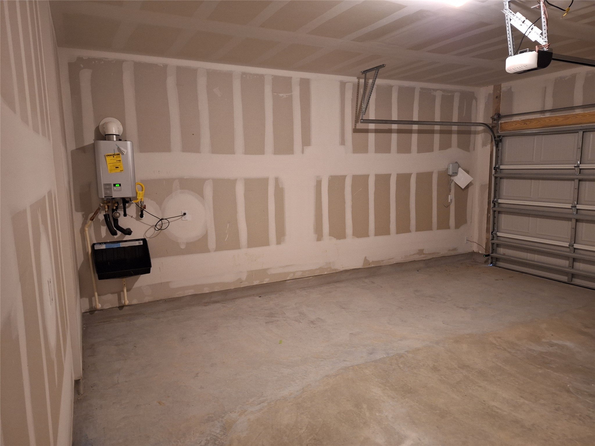 18001 Prairie Falcon Way Pflugerville, TX 78660 - Photo 23 of 38 Spacious garage featuring a concrete floor, overhead lighting, garage door opener mechanism, and a wall-mounted tankless water heater