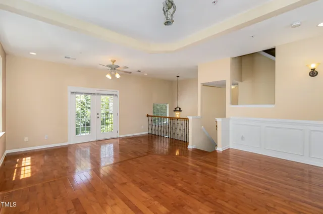 a view of empty room with wooden floor and fan