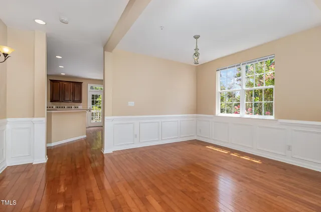 wooden floor in an empty room with a kitchen and a window