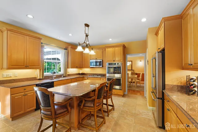 a kitchen with stainless steel appliances a dining table chairs stove and refrigerator