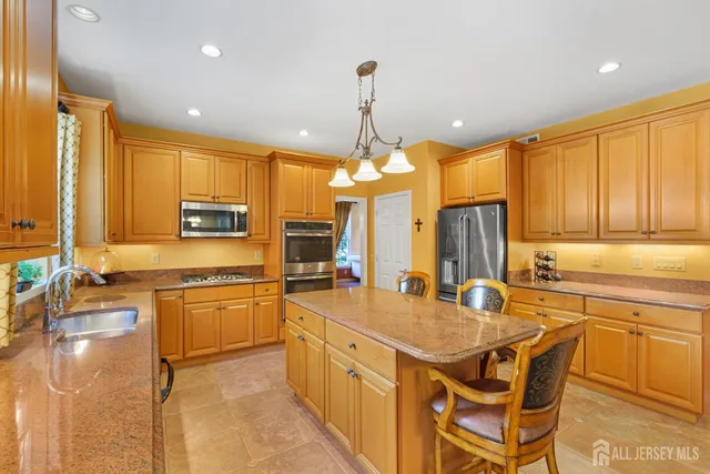 a kitchen with stainless steel appliances granite countertop a stove top oven a sink dishwasher a dining table and chairs with wooden cabinets