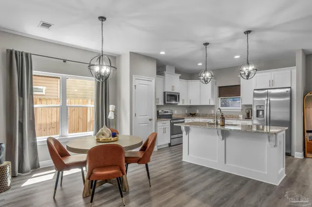 a kitchen with kitchen island a dining table chairs and wooden floor