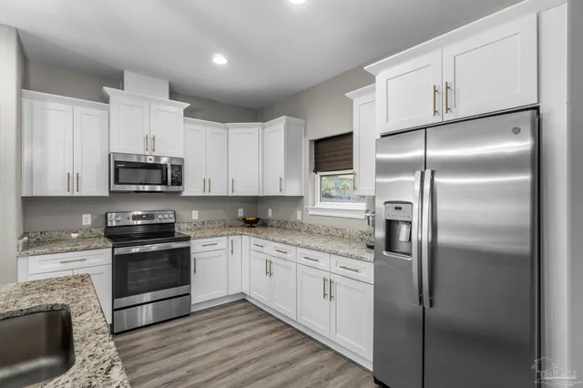 a kitchen with stainless steel appliances granite countertop a refrigerator a stove and a sink
