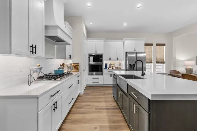 a large white kitchen with stainless steel appliances lots of counter top space