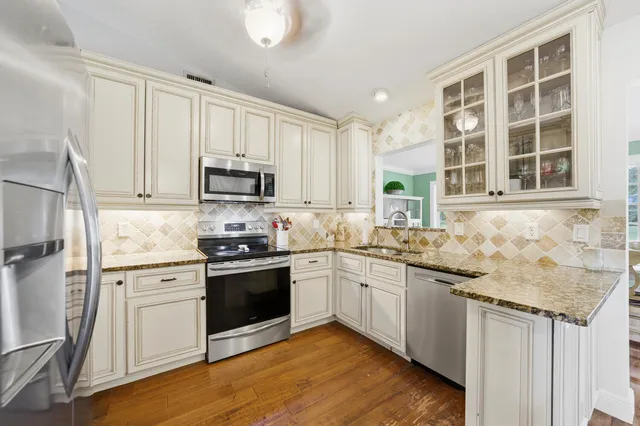 a kitchen with stainless steel appliances granite countertop wooden floors and white cabinets