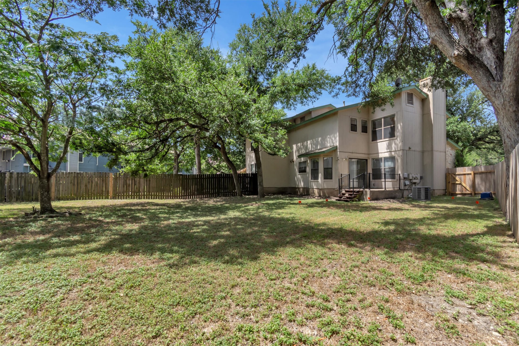 7802 Topawa Cove, Unit B Austin, TX 78729 - Photo 4 of 32 A spacious backyard provides ample green space for outdoor activities and shaded relaxation.