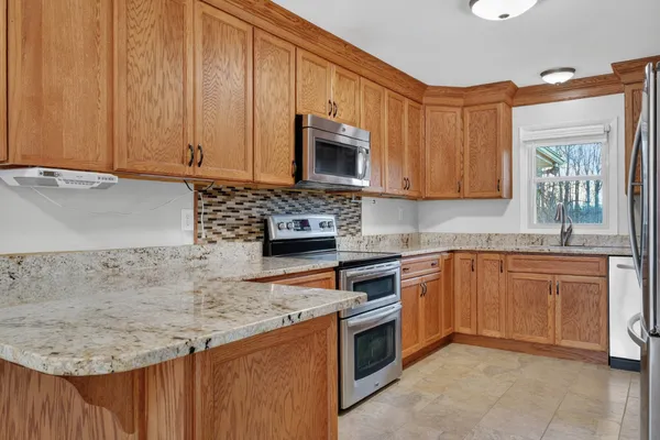 a kitchen with stainless steel appliances granite countertop a stove a sink dishwasher and a microwave oven with cabinets