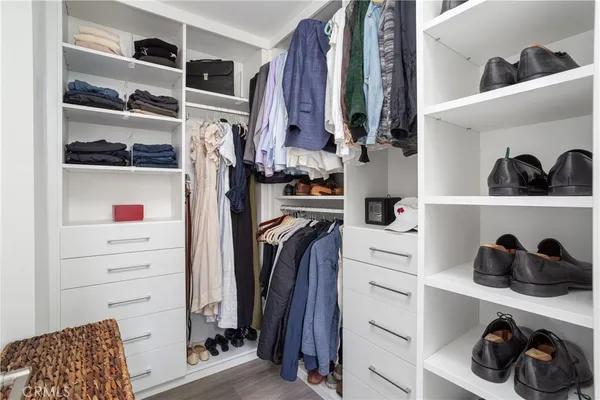 a view of walk in closet with clothes and shoes