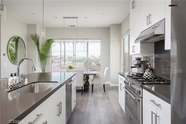 a kitchen with kitchen island granite countertop a stove a sink and wooden floors