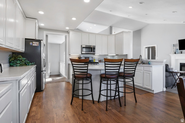 13176 Day Court Draper, UT 84020 - Photo 9 of 45 Kitchen with a breakfast bar, white cabinetry, dark wood-type flooring, stainless steel appliances, and recessed lighting