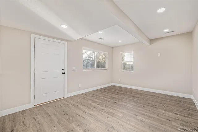 an empty room with wooden floor and windows