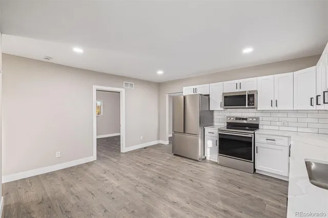 a large white kitchen with granite countertop a stove a sink and a refrigerator