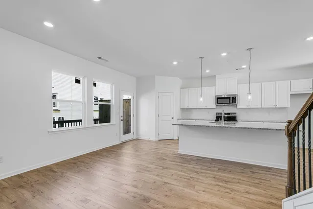 a large kitchen with cabinets wooden floor and stainless steel appliances