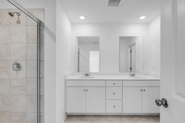 a bathroom with a double vanity sink a mirror and a bathtub