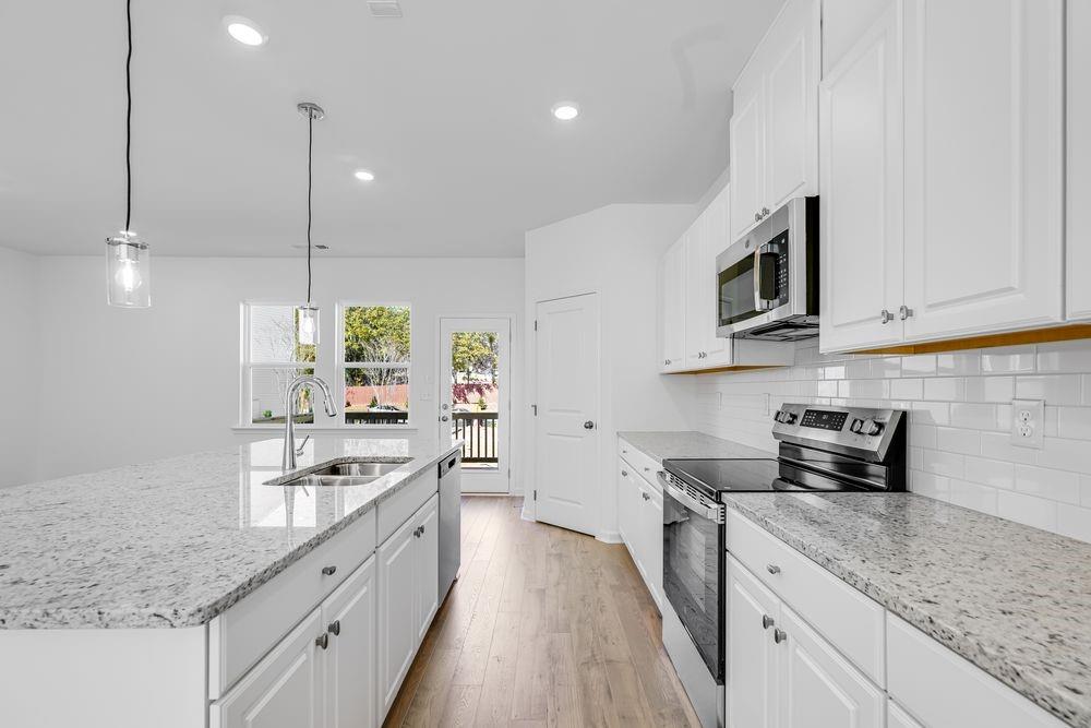 6117 Wayburn Street Tucker, GA 30084 - Photo 7 of 48 a kitchen with stainless steel appliances granite countertop a sink a stove and a wooden floors