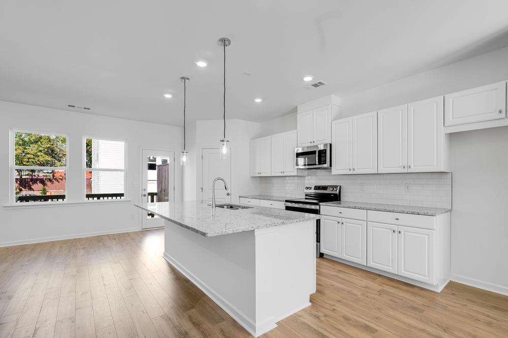 6117 Wayburn Street Tucker, GA 30084 - Photo 8 of 48 a large kitchen with stainless steel appliances granite countertop a stove a sink a refrigerator and white cabinets with wooden floor