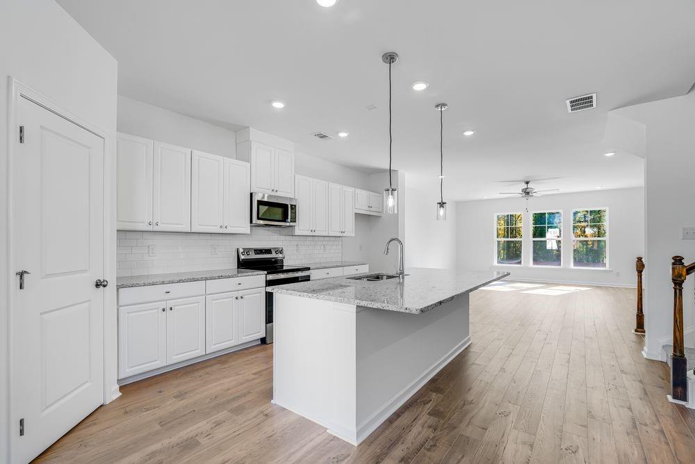 6117 Wayburn Street Tucker, GA 30084 - Photo 9 of 48 a kitchen with stainless steel appliances granite countertop a sink a stove and a wooden floors