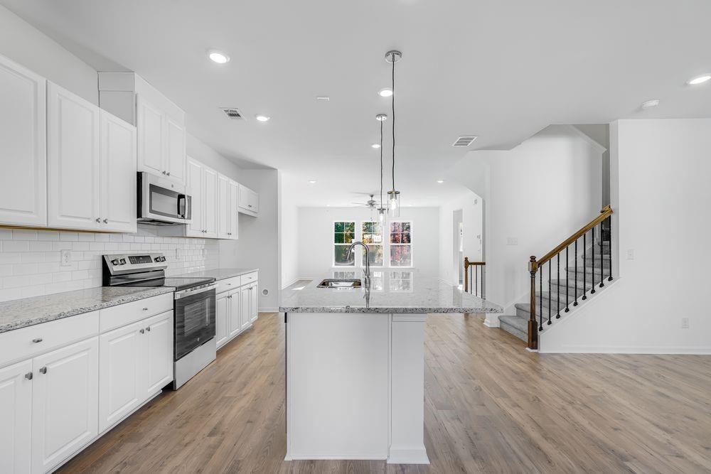 6117 Wayburn Street Tucker, GA 30084 - Photo 10 of 48 a large kitchen with cabinets a sink a window and stainless steel appliances