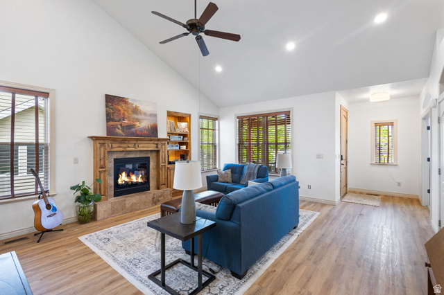 882 Sego Lily Way Mapleton, UT 84664 - Photo 6 of 41 Vaulted ceiling living area featuring wood-finish flooring, a stone-surround fireplace with a detailed wood mantel, recessed lighting, and integrated shelving