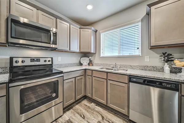 a kitchen with granite countertop a sink cabinets and stainless steel appliances