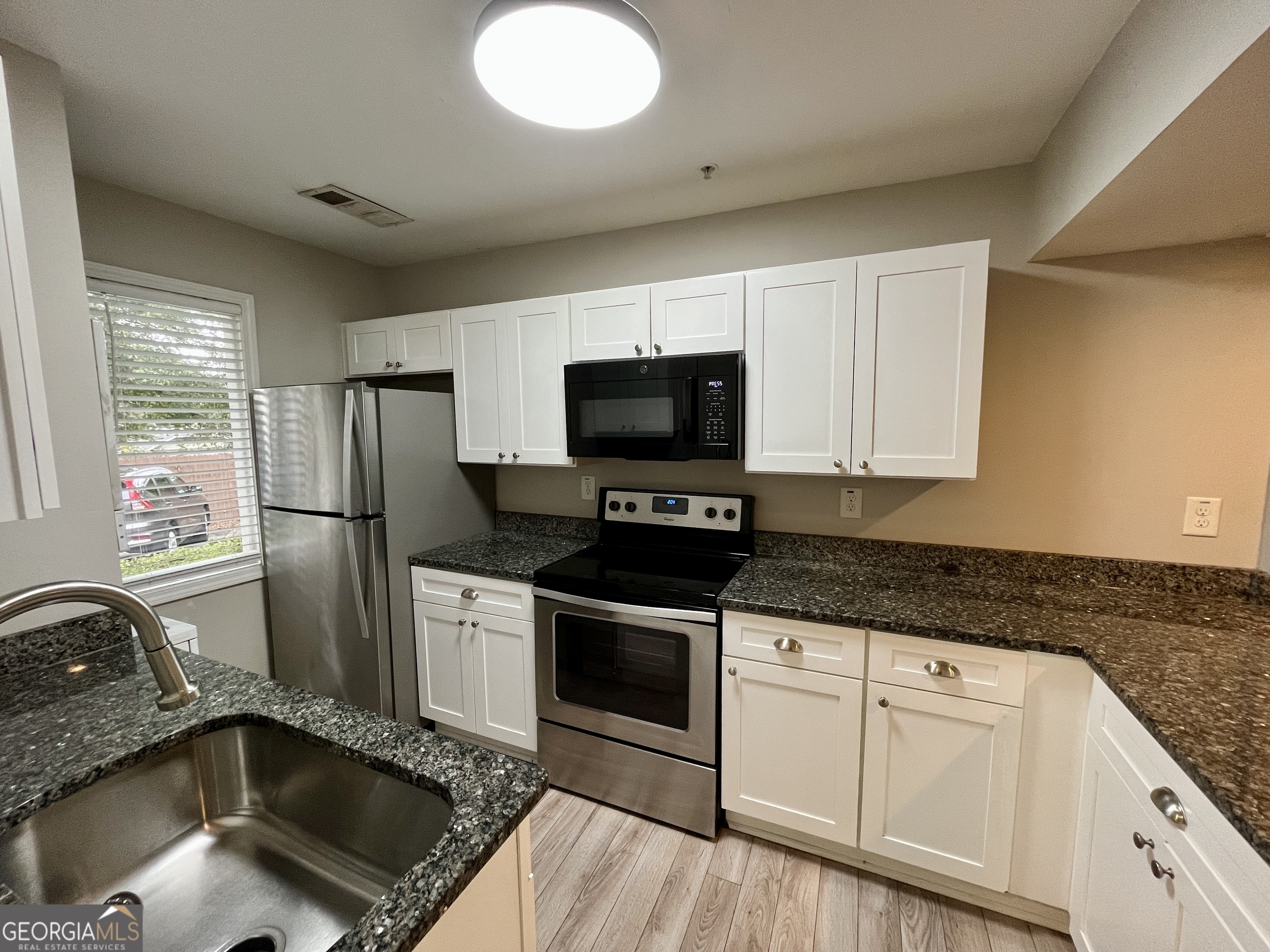 3241 Turner Street, Unit 30 East Point, GA 30344 - Photo 3 of 12 a kitchen with granite countertop a sink stainless steel appliances and white cabinets
