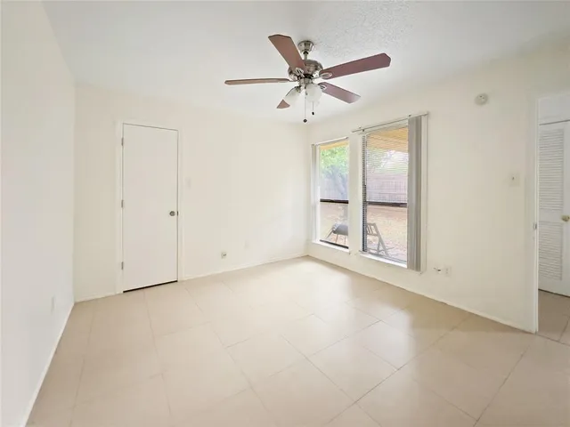 an empty room with a ceiling fan and a window